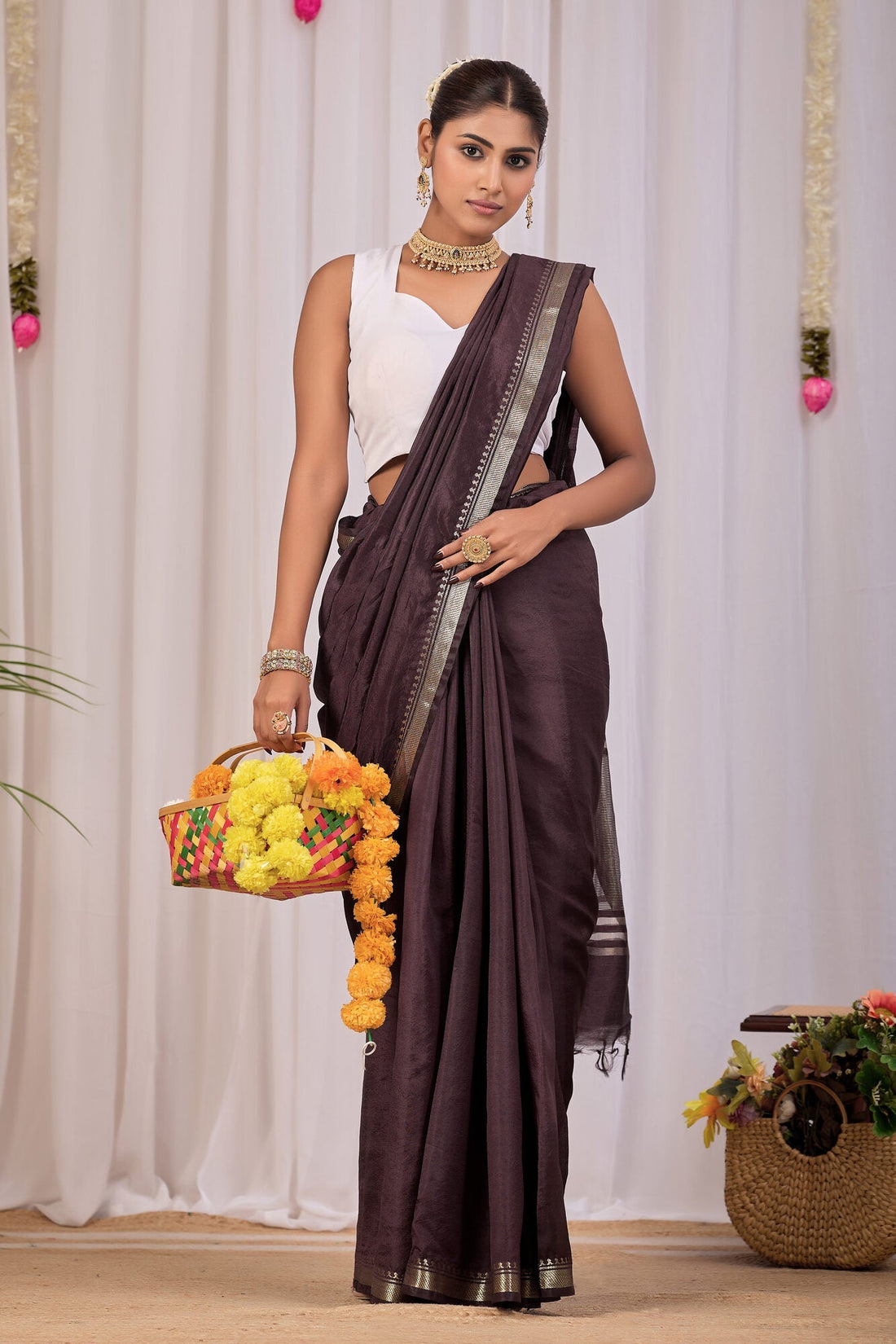 Coffee brown banana silk saree with a broad gold zari border, draped for a festive daytime function — Koshnika